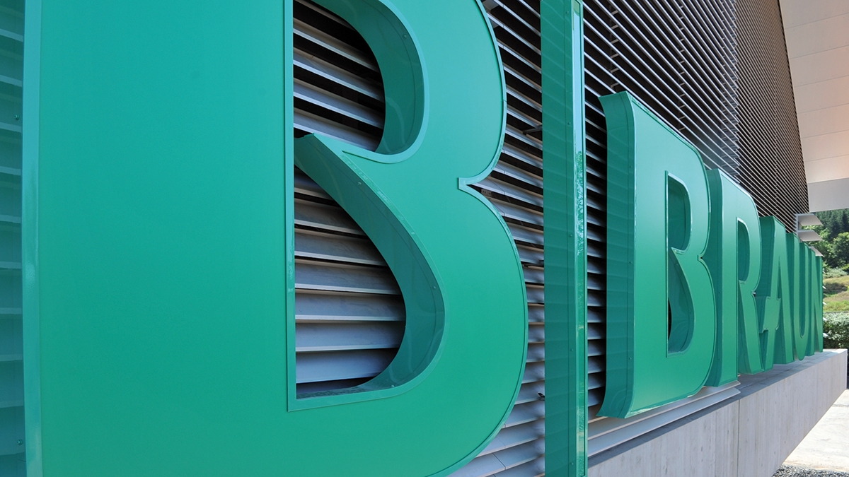 Detailný pohľad na trojrozmerné logo B. Braun na fasáde modernej budovy