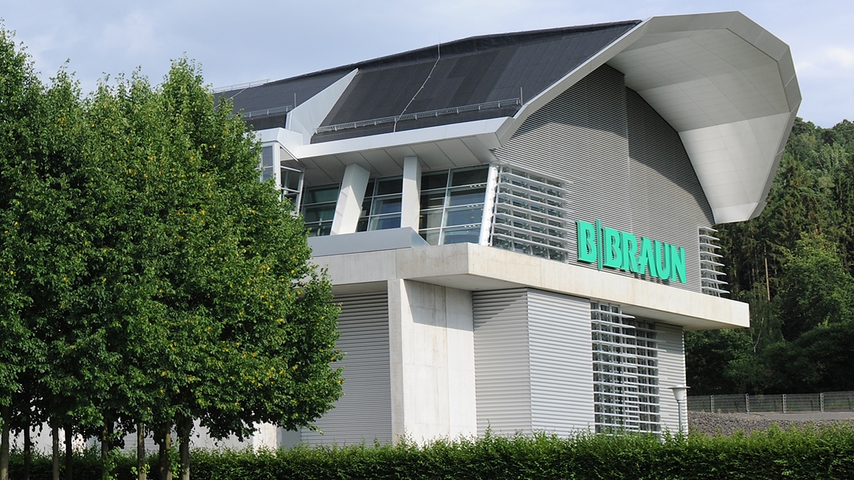 Budova návštevníckeho centra B. Braun s veľkým logom B. Braun, ktorá vyžaruje pocit pohostinnosti a otvorenosti pre všetkých, ktorí prichádzajú. 