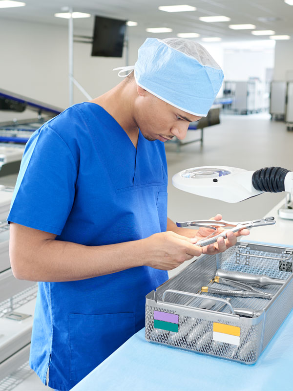 Zamestnanec oddelenia centrálnej sterilizácie kontroluje rôzne nástroje v koši